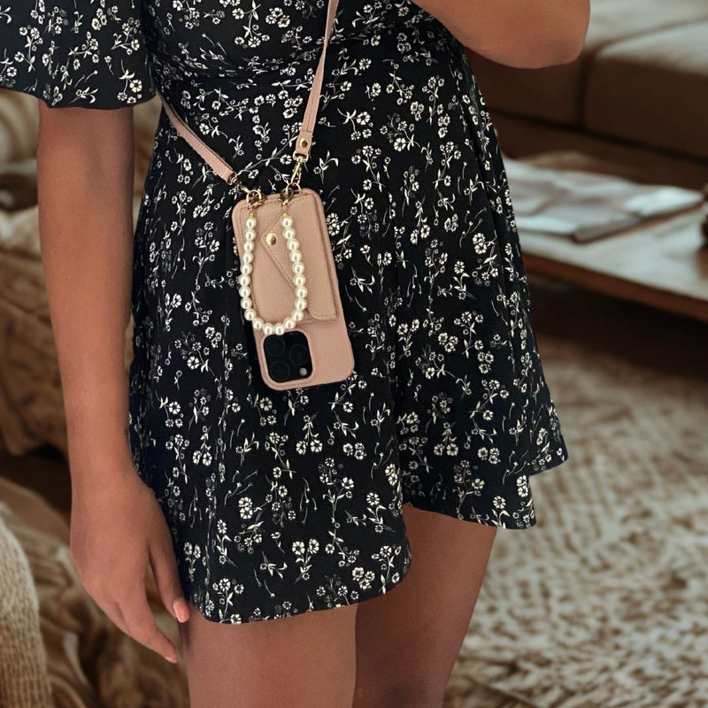 Model mit iPhone Pearl Umhängehülle in Rosa aus veganem Leder mit Perlenkette und Kartenfach – getragen über dem Kleid

